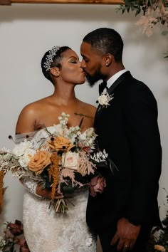 a bride and groom kissing in front of flowers