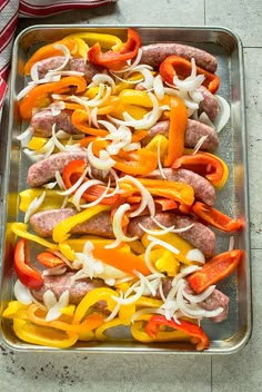 hot dogs with peppers and onions on a baking sheet ready to go into the oven