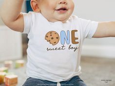 a baby wearing a one sweet boy shirt with a cookie on it's chest