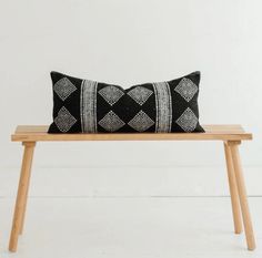 a black and white pillow sitting on top of a wooden bench