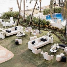 a living room with white couches and tables next to a swimming pool in the background