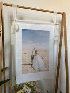 a wedding photo hanging on a wall next to flowers