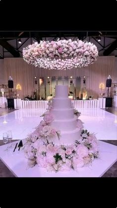 a white wedding cake sitting on top of a table covered in pink and white flowers