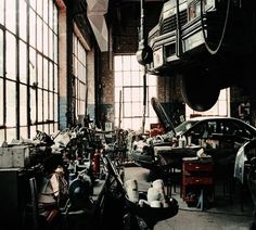 a garage filled with lots of different types of cars and tools on the floor in front of large windows