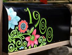 a black mailbox with colorful flowers painted on it's side and the number one