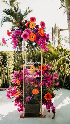 an arrangement of flowers on display in front of some palm trees and other greenery