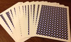 five cards with blue and yellow designs on them sitting on a table top next to a pen