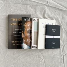 four books are lined up on a white sheet, one is black and the other is gray