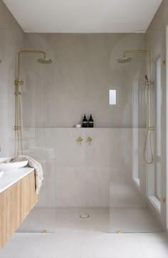 a white bathroom with two sinks and a shower in the middle is seen from across the room