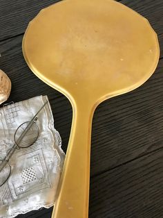 a yellow spatula sitting on top of a wooden table next to a pair of glasses