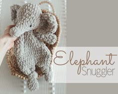 an elephant stuffed animal sitting on top of a basket next to a person's hand