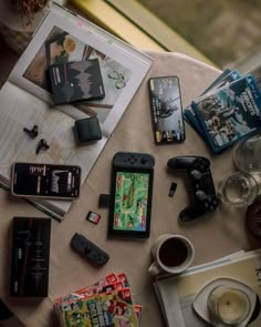 a table topped with lots of different types of electronic devices and books on top of it