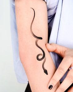 a woman is holding her arm with a snake tattoo on it's left arm