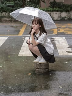 a woman kneeling down with an umbrella in the rain