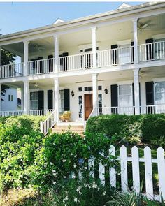 a large white house with black shutters and balconies