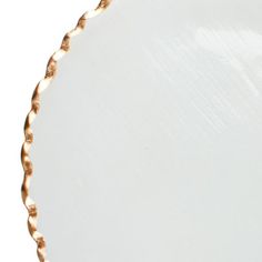 an empty white plate with gold trimmings on the edges and bottom, in front of a white background