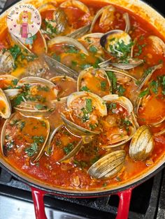 a pan filled with clams and sauce sitting on top of a stove next to a red spatula