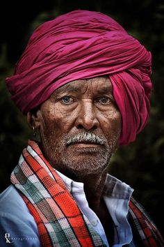 an old man with a pink turban on his head is looking at the camera