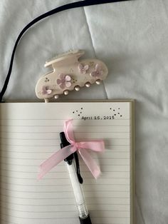 an open notebook with a pink ribbon tied around it and a toy car on top