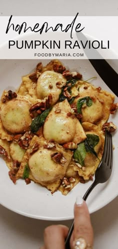 a white plate topped with ravioli covered in cheese and nuts next to a fork