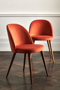 two orange chairs sitting next to each other on top of a hard wood floored floor