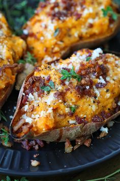 baked potatoes with bacon and cheese on a black plate, garnished with parsley