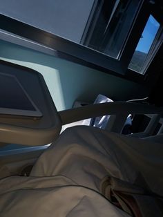 an empty hospital bed with white sheets and pillows on it's sides, in front of a window