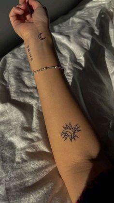 a woman's arm with a small sun and moon tattoo on her left arm