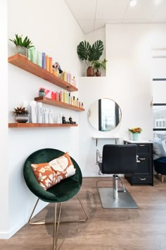 a room with a chair, mirror and shelves filled with hair care products on the wall