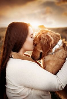 a woman is kissing her dog on the nose while it looks like she's hugging him