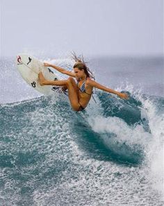 a woman riding a wave on top of a white surfboard in the middle of the ocean