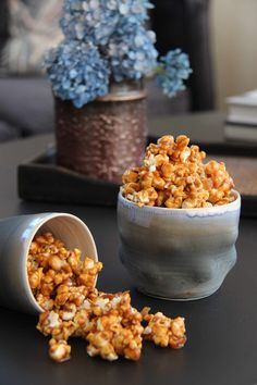 a bowl filled with popcorn sitting on top of a table next to a potted plant