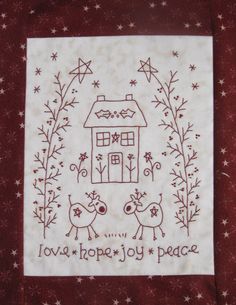 a red and white quilted wall hanging with a house on it