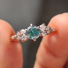 a woman's hand holding an engagement ring with blue and white diamonds on it