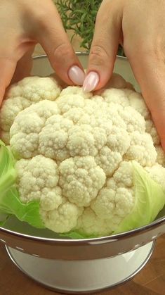 two hands touching cauliflower in a silver bowl