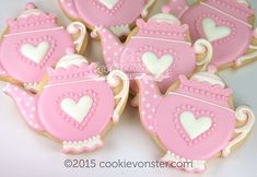 pink and white decorated cookies in the shape of teapots