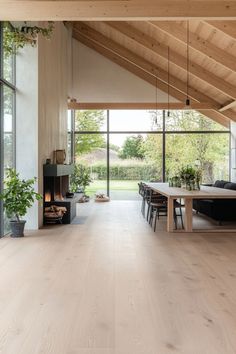 an open living room and dining area with wood flooring, large windows, and fireplace