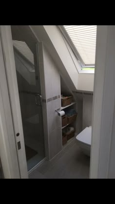 a white toilet sitting under a bathroom window next to a walk in shower and sink