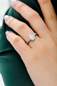 a woman's hand with a diamond ring on her left hand, wearing a green dress