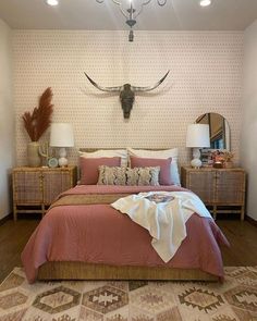 a bedroom with a bed, two nightstands and a cow skull on the wall