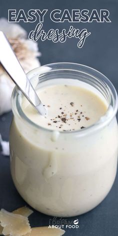 an easy caesar dressing recipe in a glass jar with a spoon and garlic on the side