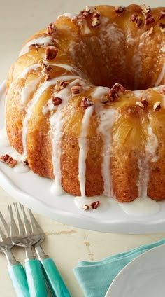 a bundt cake with white icing and pecans on top sitting on a plate