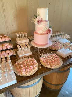 a table topped with lots of cakes and cupcakes on top of wooden barrels