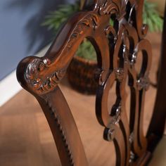 a wooden chair sitting on top of a hard wood floor next to a potted plant