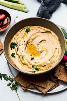 hummus in a bowl surrounded by crackers and vegetables