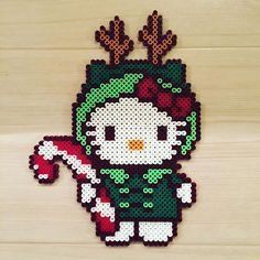 a hello kitty christmas ornament made out of perler beads on a wooden surface