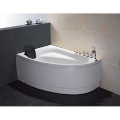 a white bath tub sitting on top of a black floor next to a tiled wall