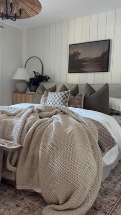 a bedroom with a bed covered in blankets and pillows