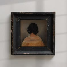 a portrait of a woman in a black frame hanging on the side of a wall