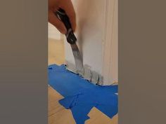 a person using a pair of scissors to cut out blue tape on the side of a wall